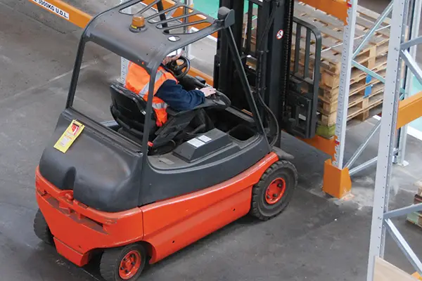 A forklift operator picking up a pallet from some racking
