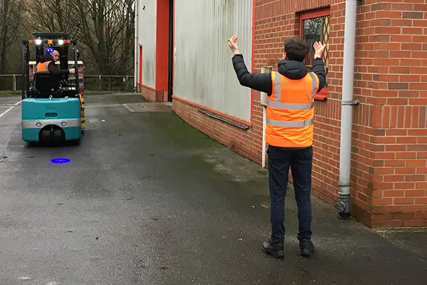 A banksman guiding a forklift operator